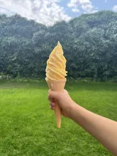 sárgabarack lágyfagylalt tölcsérben, egy kézben tartva a tölcsért