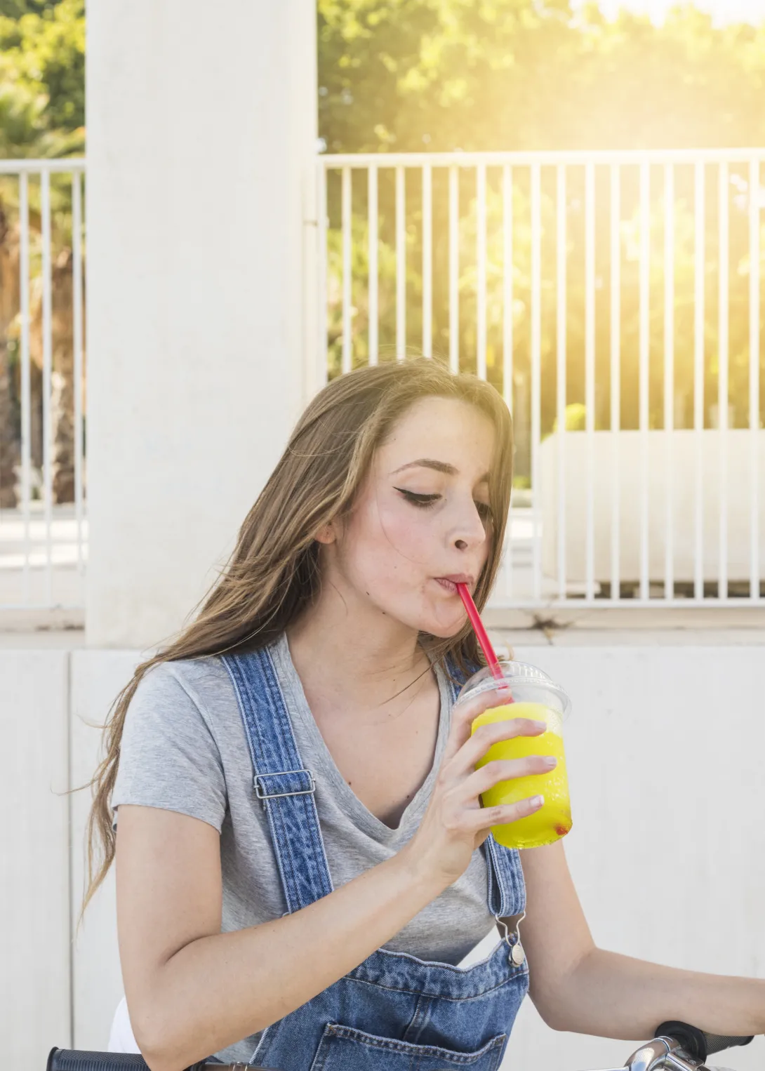 Bicikliző lány jégkását iszik szívószállal